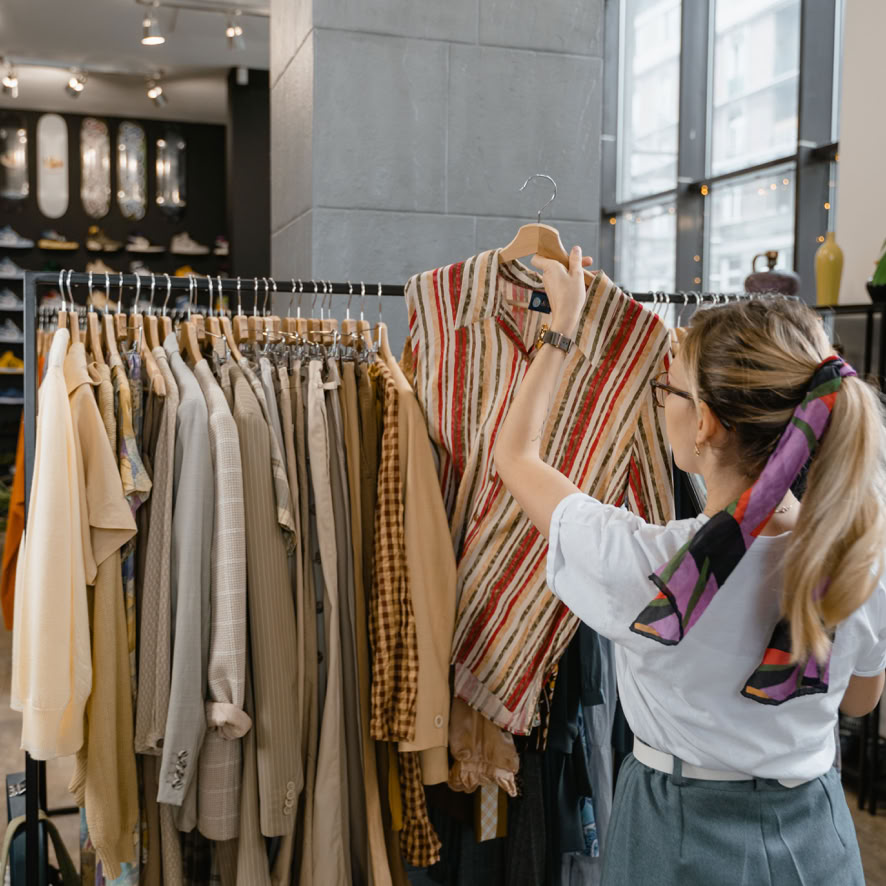 Woman in White Sleeve Shirt Standing Near Clothes Rack